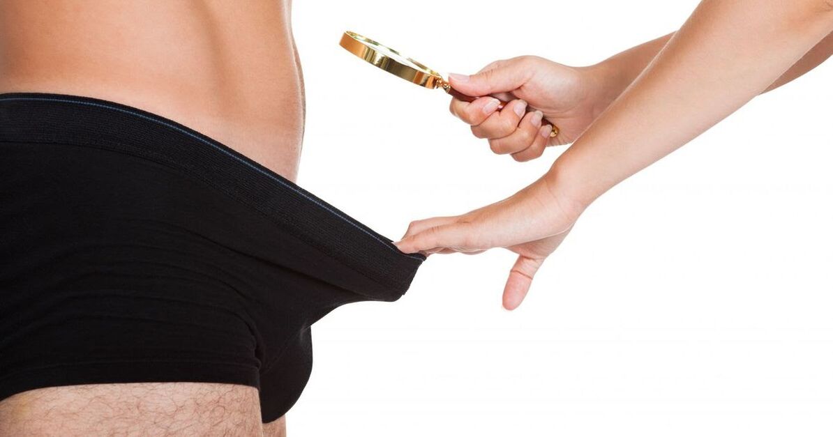 Una ragazza guarda un piccolo pene attraverso una lente d'ingrandimento